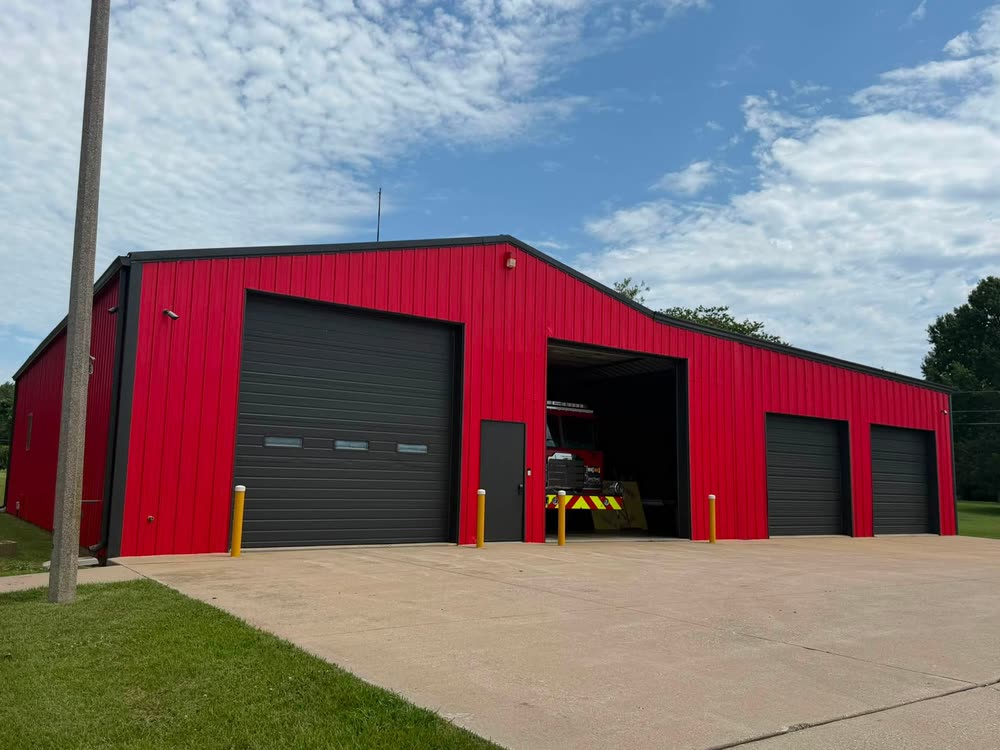 Station 2, a red metal building with four apparatus bay doors, one open with a fire truck inside